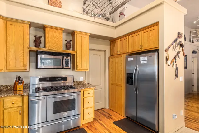 a kitchen with stainless steel appliances granite countertop a refrigerator a stove and a sink with wooden floor