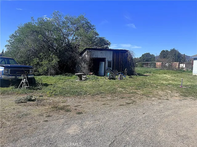 a view of a backyard with wooden fence and large trees