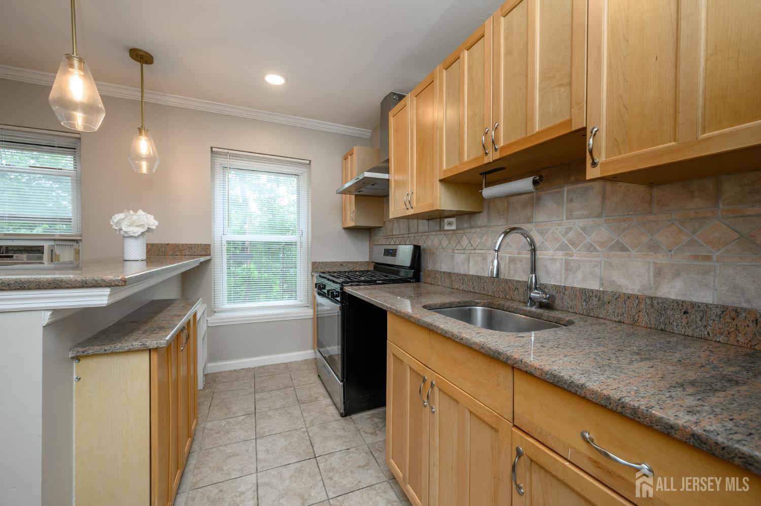 243 Johnson Avenue, Unit L5 Hackensack, NJ 07601 - Photo 11 of 24 a kitchen with granite countertop a sink stove and cabinets