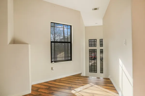 a view of a bedroom with wooden floor and windows