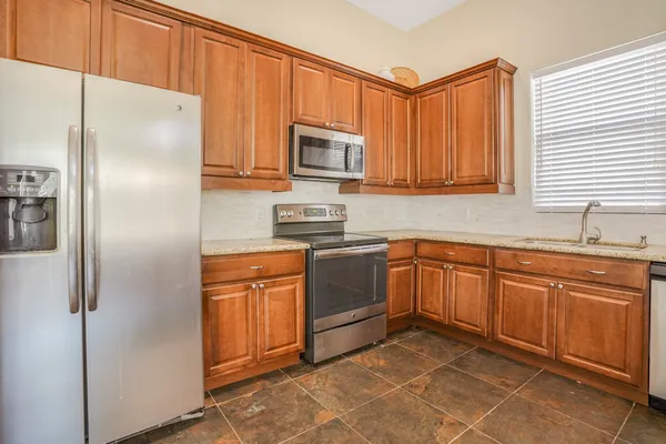 a kitchen with stainless steel appliances granite countertop a refrigerator and a sink