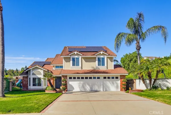 a view of a white house with a big yard and palm trees