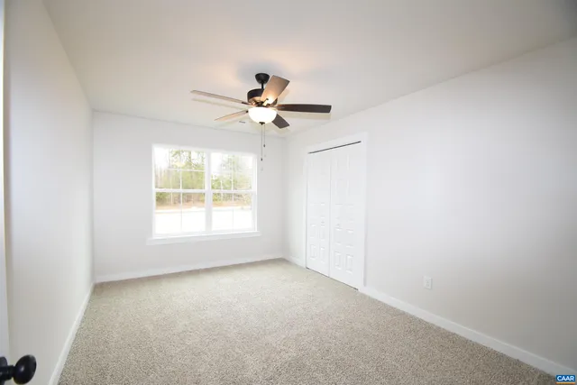 an empty room with a window and a ceiling fan