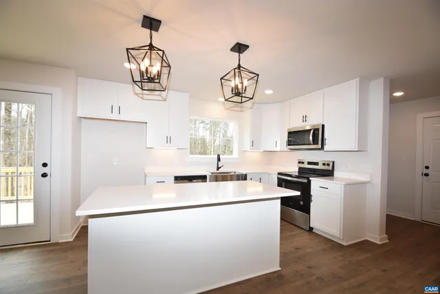 a kitchen view with stainless steel appliances a stove a sink dishwasher a refrigerator and microwave with wooden floor