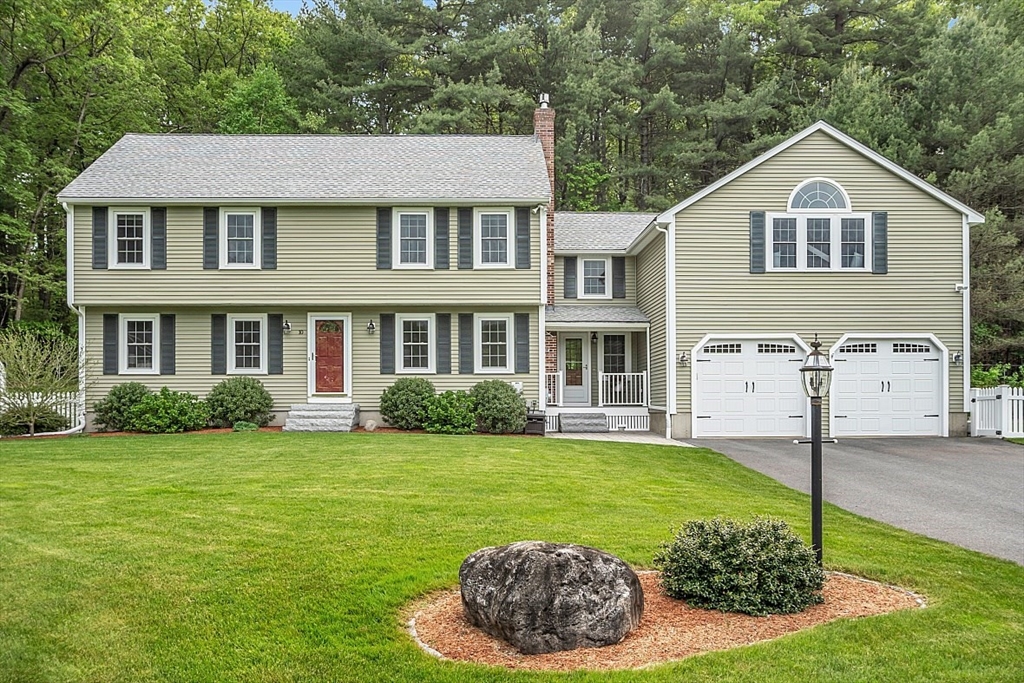 a view of a yard in front of a brick house with plants and large trees