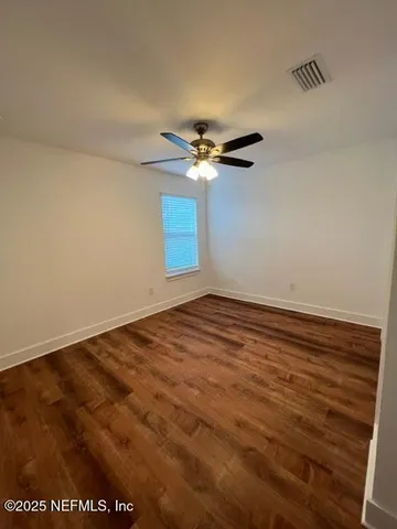 an empty room with wooden floor and ceiling fan