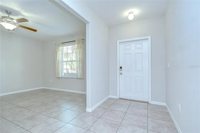 a view of an empty room with window and chandelier fan
