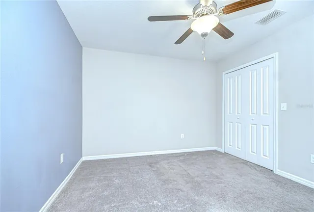 an empty room with a ceiling fan and a window