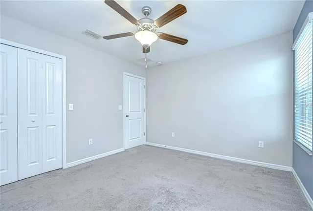 an empty room with windows and fan