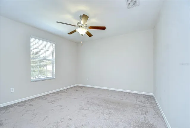 an empty room with a window and a ceiling fan
