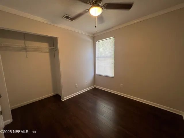 an empty room with wooden floor a ceiling fan and windows