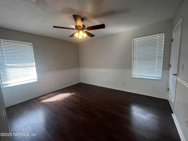 an empty room with wooden floor and windows
