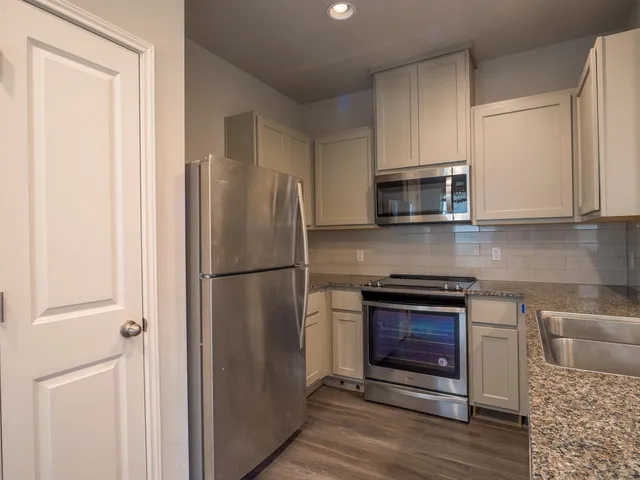 a kitchen with stainless steel appliances granite countertop a refrigerator and a stove top oven