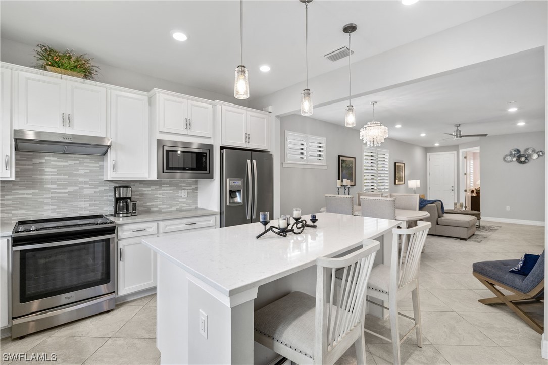 11237 Carlingford Road Fort Myers, FL 33913 - Photo 19 of 38 a kitchen with stainless steel appliances kitchen island a table chairs stove and microwave
