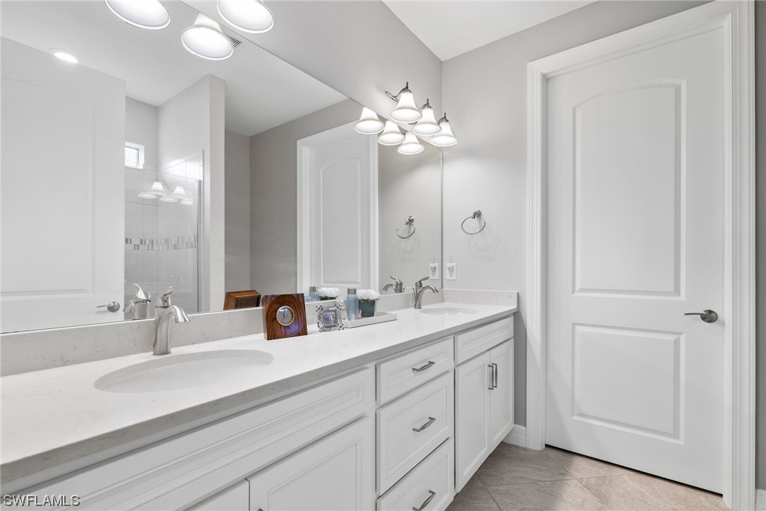 11237 Carlingford Road Fort Myers, FL 33913 - Photo 21 of 38 a bathroom with double vanity sinks a vanity a lamp and a mirror