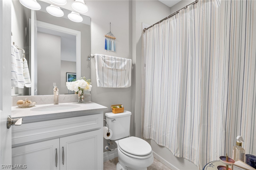 11237 Carlingford Road Fort Myers, FL 33913 - Photo 10 of 38 a bathroom with a sink a toilet a mirror and shower curtain