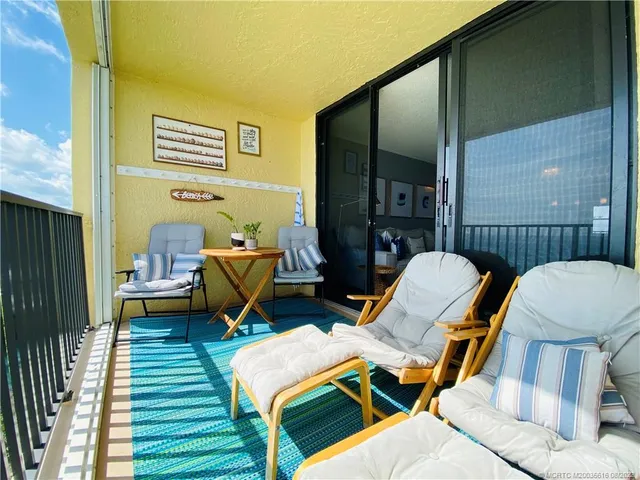 a balcony with wooden floor table and chairs