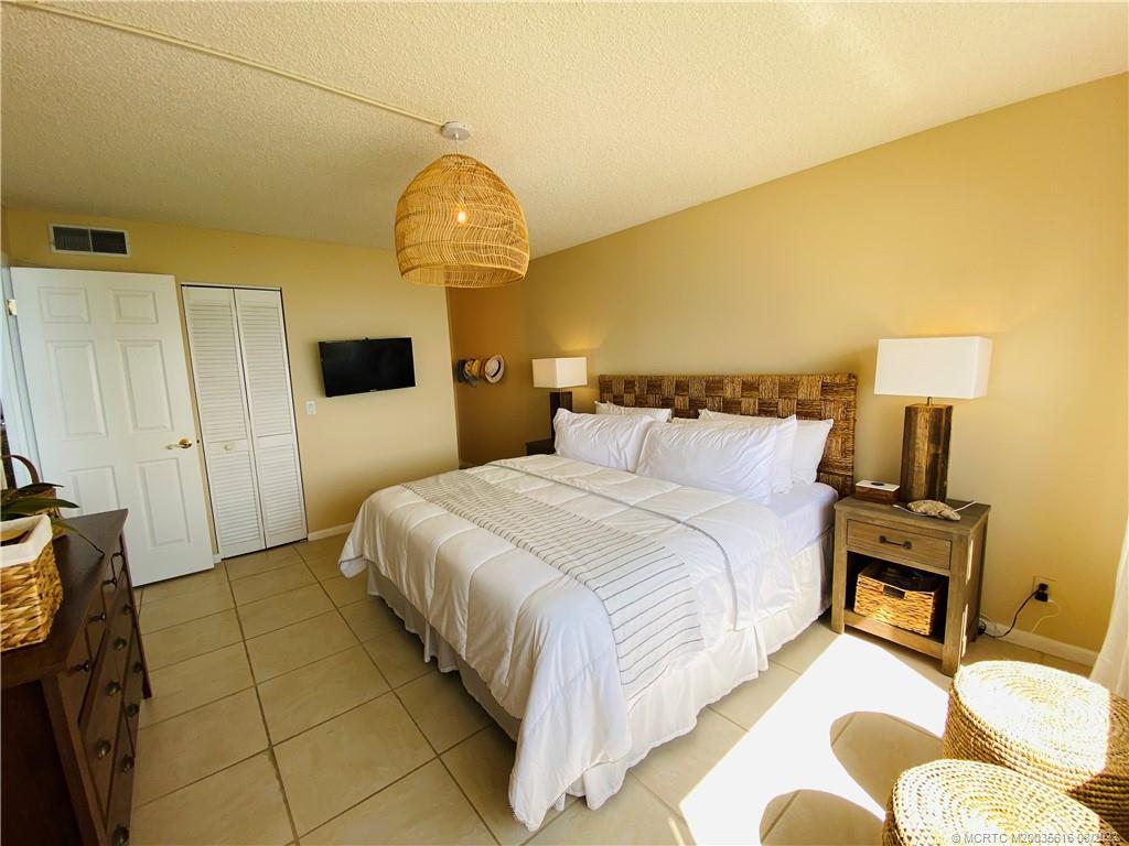 7380 South Ocean Drive, Unit 718A Jensen Beach, FL 34957 - Photo 30 of 58 a spacious bedroom with a bed and a lamp