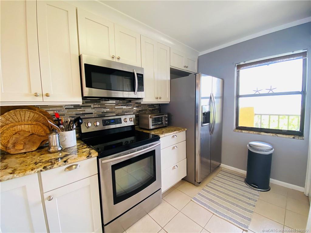 7380 South Ocean Drive, Unit 718A Jensen Beach, FL 34957 - Photo 5 of 58 a kitchen with granite countertop a stove top oven microwave and refrigerator