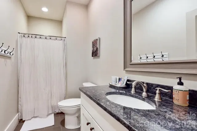 a bathroom with a granite countertop sink a toilet and a mirror
