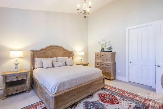 a bedroom with a bed a dresser and a chandelier