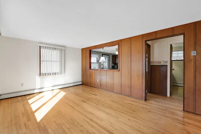 a view of an empty room with glass door and wooden floor