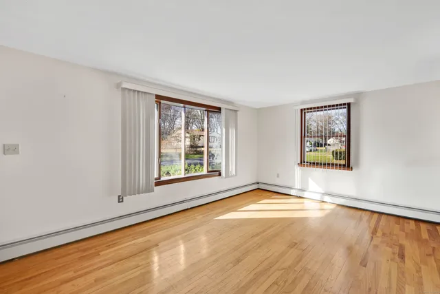 a view of an empty room with a window and wooden floor