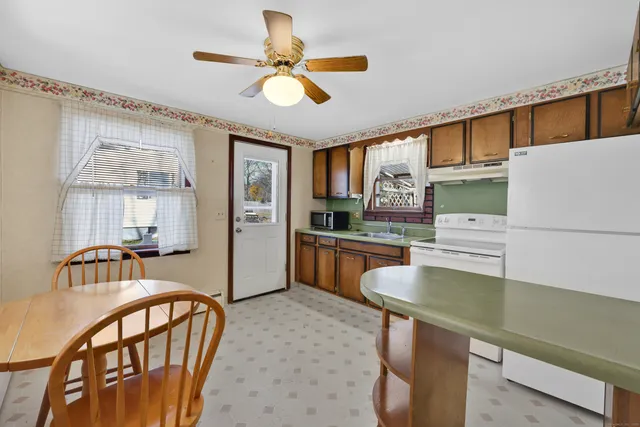 a kitchen with stainless steel appliances kitchen island granite countertop a table chairs in it and wooden floors
