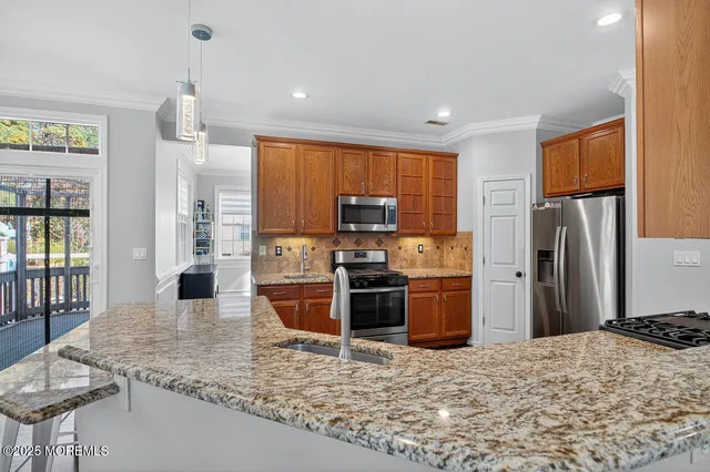 a kitchen with stainless steel appliances granite countertop a refrigerator stove top oven dining table and chairs