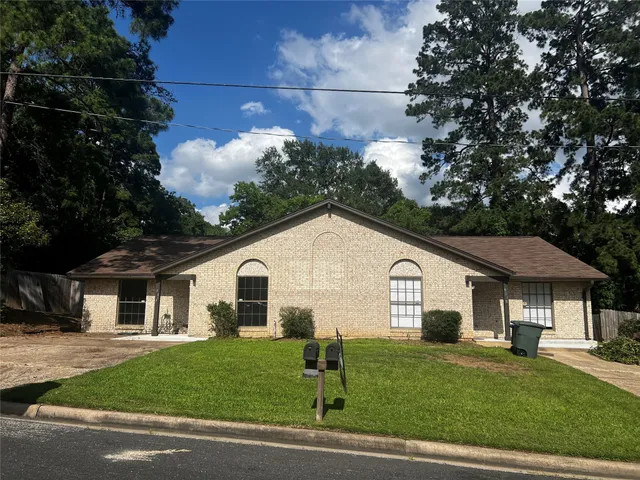 a view of a white house in front of a big yard with large trees