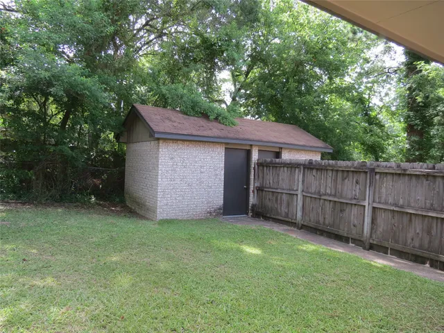 a backyard of a house with large trees and wooden fence