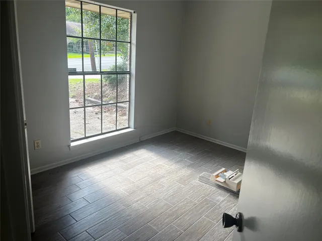 an empty room with wooden floor cabinet and windows