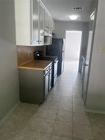 a kitchen with stainless steel appliances a sink a stove a refrigerator a microwave oven with white cabinets