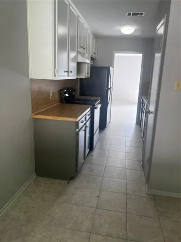 a kitchen with stainless steel appliances a sink a stove a refrigerator a microwave oven with white cabinets