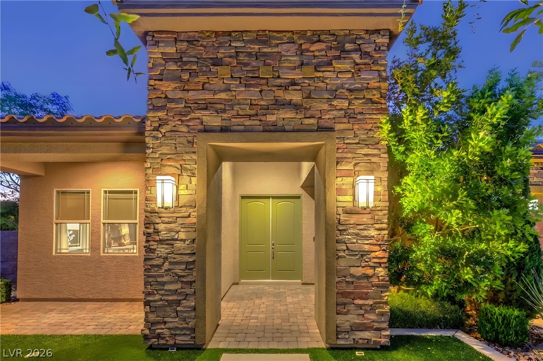 7119 Arabian Ridge Street Las Vegas, NV 89131 - Photo 6 of 73 A welcoming entry features stone veneer, inviting green doors, and warm exterior lighting.