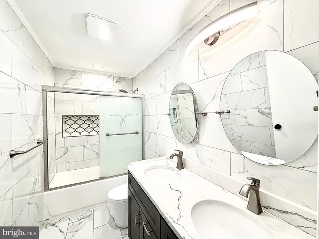 a bathroom with a sink toilet double vanity and tub