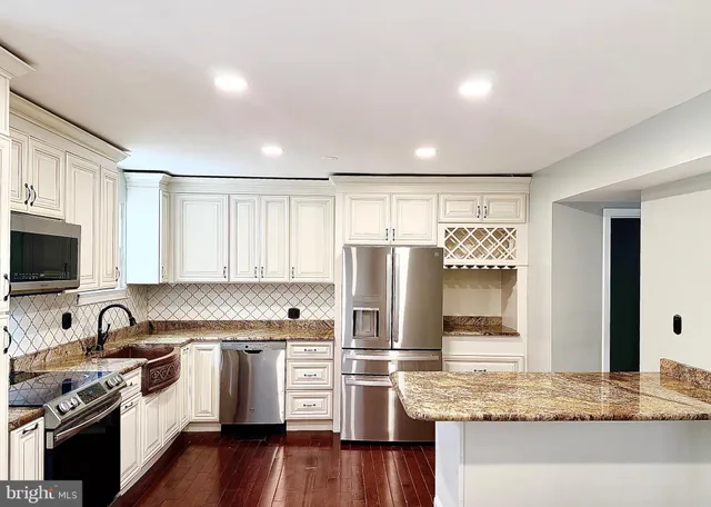 a kitchen with granite countertop a refrigerator stove and sink with wooden floor