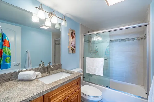 a bathroom with a granite countertop sink a toilet a mirror and shower