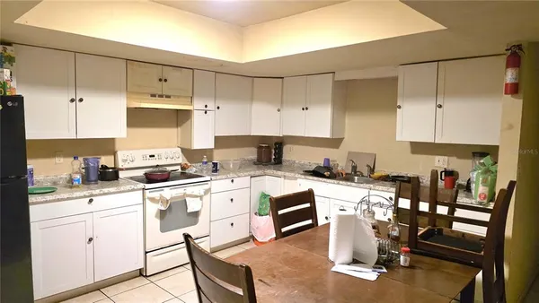 a kitchen with a stove a sink and white cabinets