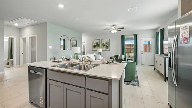 a kitchen with stainless steel appliances a sink a stove a refrigerator cabinets and chairs