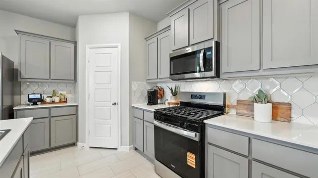 a kitchen with stainless steel appliances granite countertop a sink a stove a refrigerator cabinets and chairs