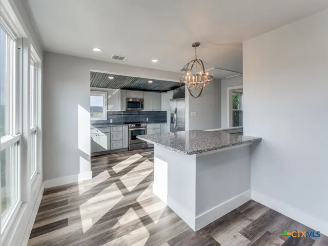 a view of a kitchen with granite countertop stainless steel appliances and a chandelier