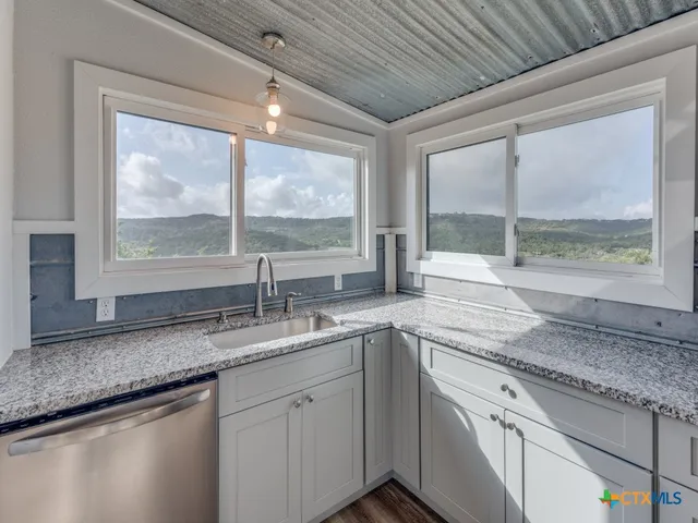 a kitchen with granite countertop a sink window and cabinets