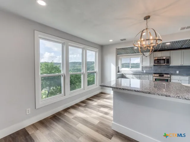 a very nice looking kitchen with granite countertop a stove and a large window