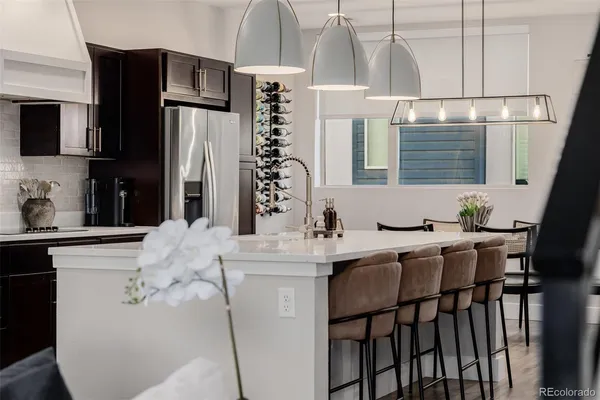 a kitchen with stainless steel appliances kitchen island granite countertop a refrigerator a sink a stove and white cabinets