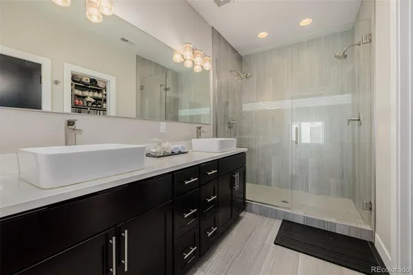 a bathroom with a sink double vanity granite tub shower and a mirror