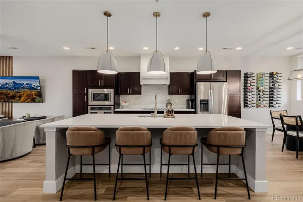 a kitchen with stainless steel appliances kitchen island granite countertop a dining table chairs and sink