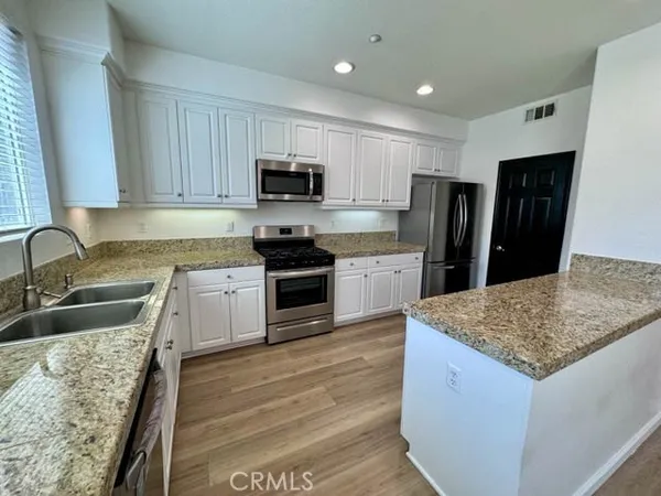 a kitchen with stainless steel appliances granite countertop wooden cabinets granite counter tops and a hard wood floors