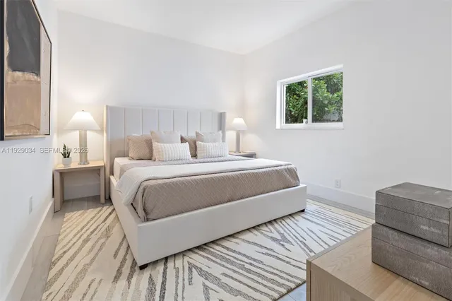 a bedroom with a bed lamp and a large window