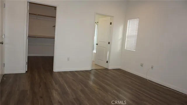 a view of an empty room with wooden floor and closet